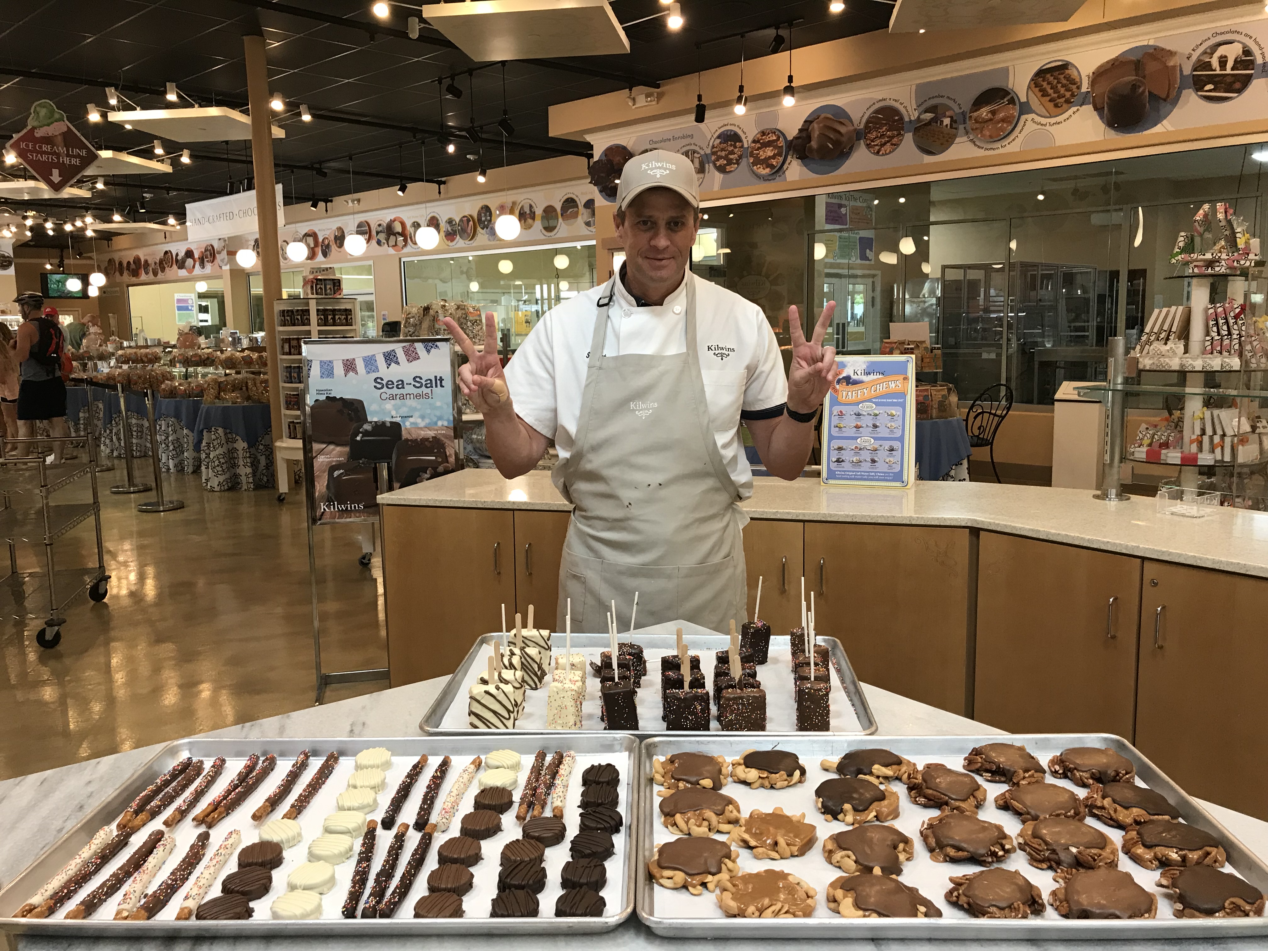 Photo of store owner standing behind marble table full of made-in-store products