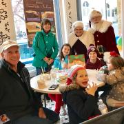 A picture of Santa and Mrs. Claus with a family at Kilwins