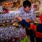 Photo of child selecting bagged candies from table with dad