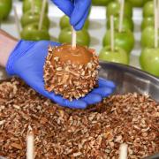 Photo of Pecan Caramel Apple being rolled in Caramel